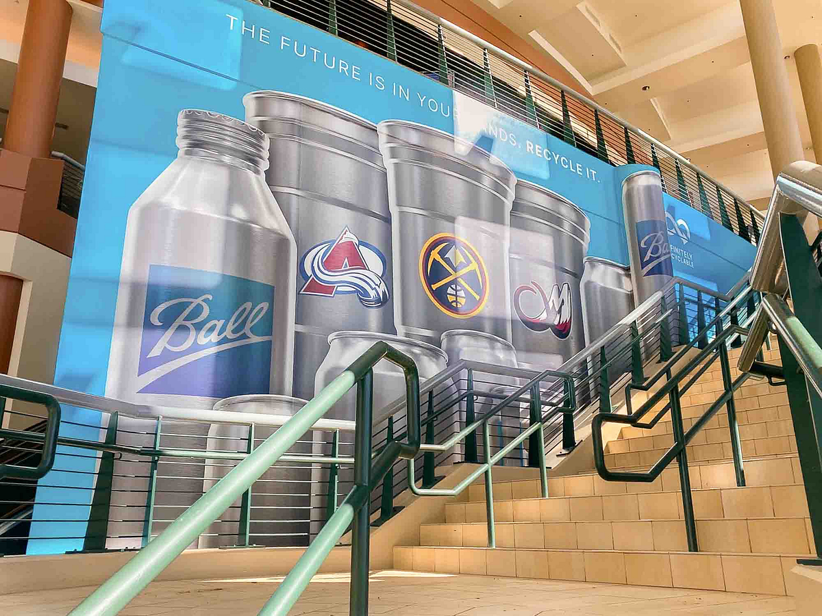 Mural at Ball Arena featuring aluminum cups with logos of Colorado sports teams.